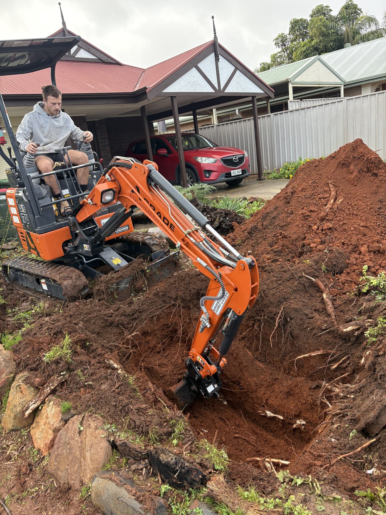 Mini excavator digging red soil at an Adelaide home